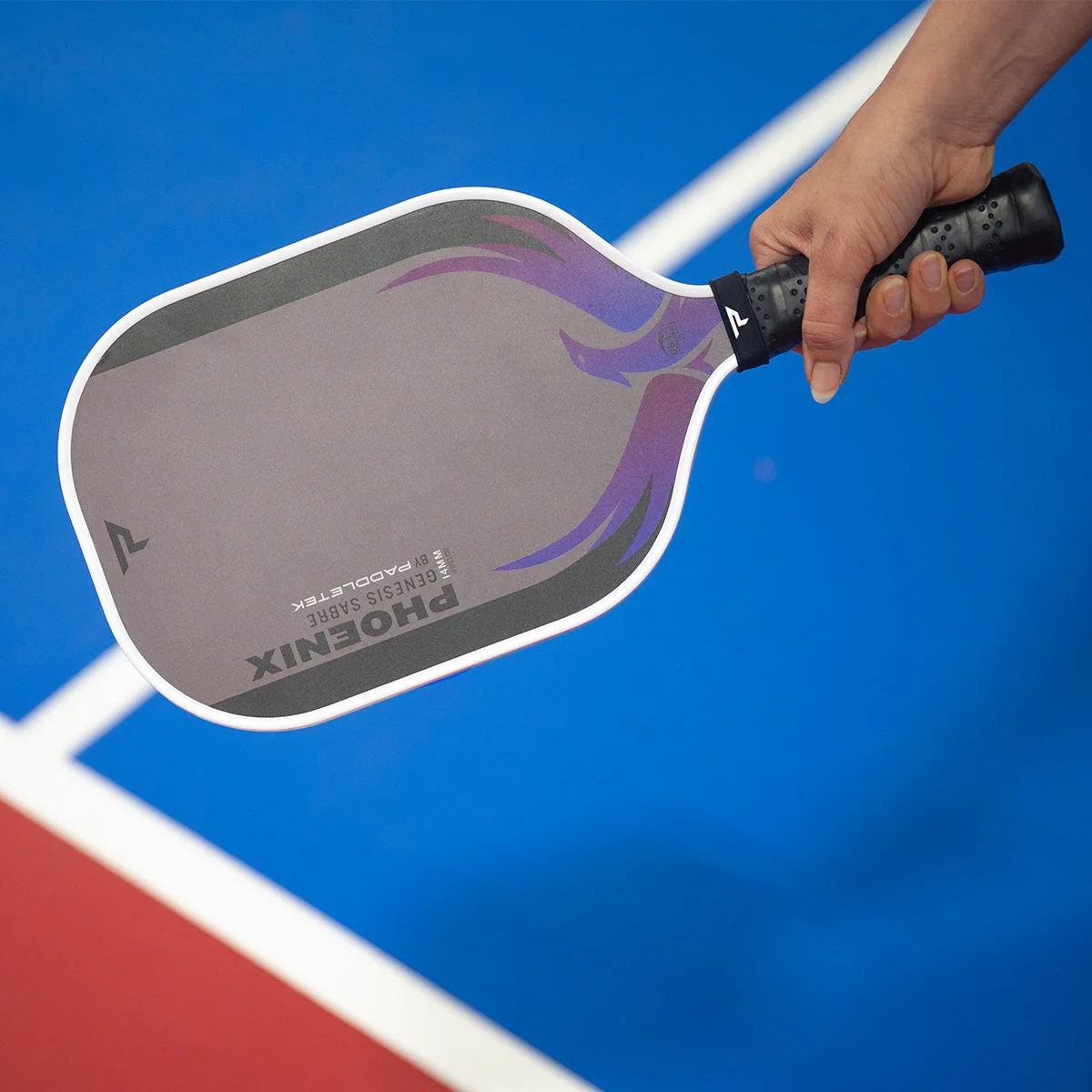 Tay cầm vợt Phoenix Sabre Carbon dáng dài trên nền sân xanh