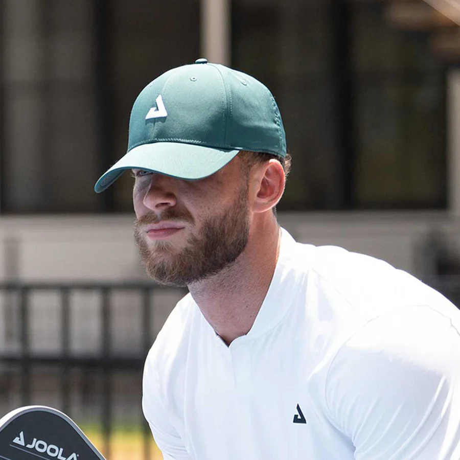 Người chơi đội mũ JOOLA Essential Cap Club Green ngoài trời, cầm vợt JOOLA